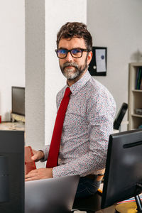 Portrait of businessman sitting at his desk holding his smartphone