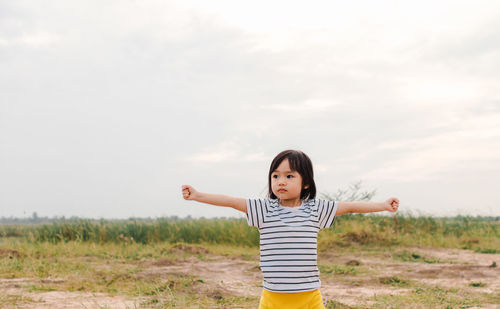 Girl with arms outstretched standing on field