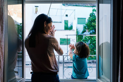 Rear view of women standing in glass window