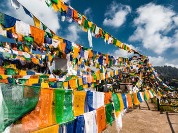 Multi colored flags hanging in row against sky