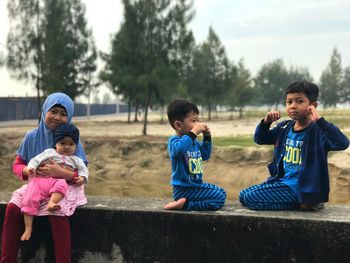 Children playing while sitting on retaining wall