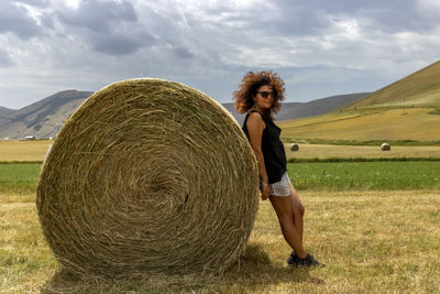 Young woman standing on field against sky