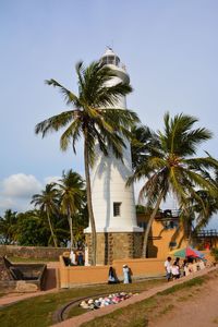 People by palm trees against sky