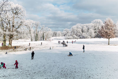 People on snow covered field against sky