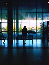 Rear view of silhouette man walking on window at airport