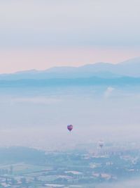 Hot air balloon flying over city against sky