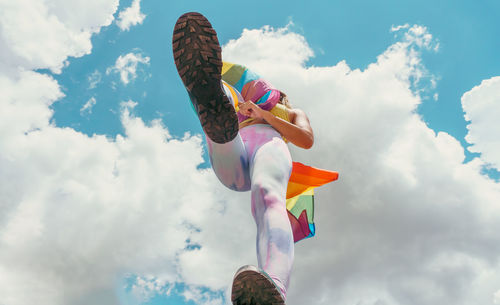 Low angle view of woman holding american flag against sky