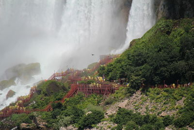 Tourists walk close to niagara falls in yellow raincoats 