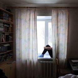 Rear view of woman looking through window at home