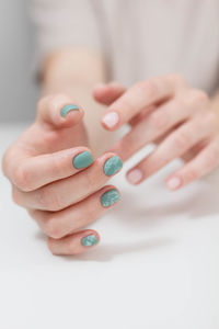 Midsection of woman with nail polish against white background