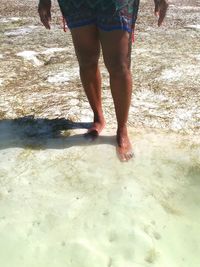 Low section of man standing on wet beach