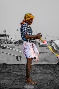 Man working with umbrella standing against sky