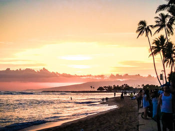 Group of people on beach during sunset