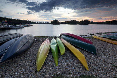 Boats moored in lake against sky during sunset