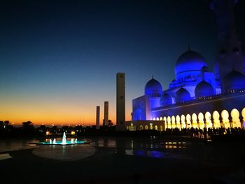 Illuminated building against blue sky at night