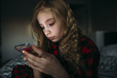 Close-up of girl using mobile phone while sitting on bed at home