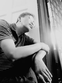 Young man looking away while sitting at home