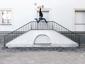 Man with balloon jumping over steps by door of building