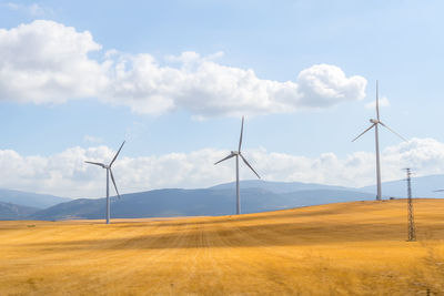 Windmills on field against sky