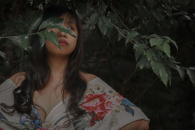 Woman looking away while standing against plants