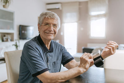 Smiling senior man taking his blood pressure