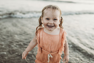 Portrait of toddler girl smiling in ocean at sunset