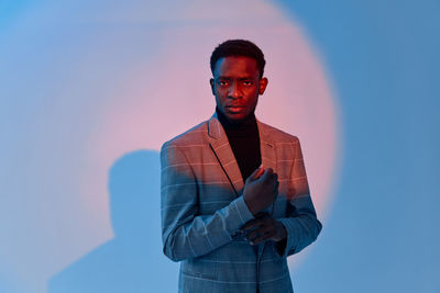 Portrait of young man standing against blue background