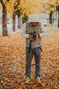 Full length of photographer photographing during autumn