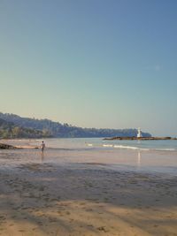 People walking on beach against clear sky