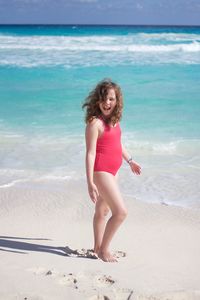 Happy young woman standing on beach against sky