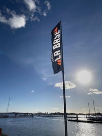 Low angle view of flag by sea against sky