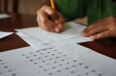 Midsection of boy writing on paper at home