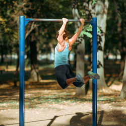 Woman exercising on horizontal bar outdoors in the fall, in public park