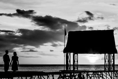 Silhouette people standing on beach by sea against sky