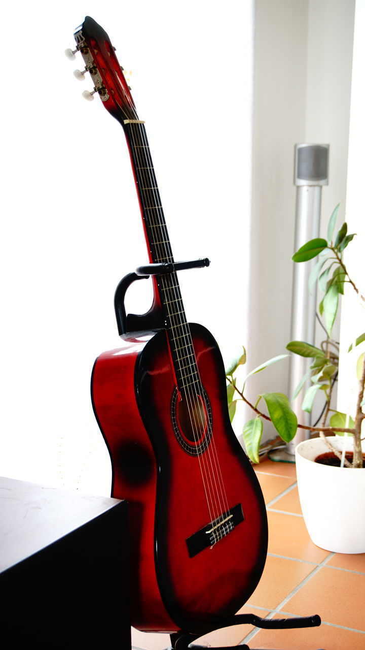 CLOSE-UP OF GUITAR ON TABLE AGAINST WALL