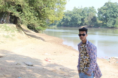 Full length of man wearing sunglasses standing by lake