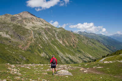 Rear view of woman standing on mountain against sky. scenic view of trekking on mountain 
