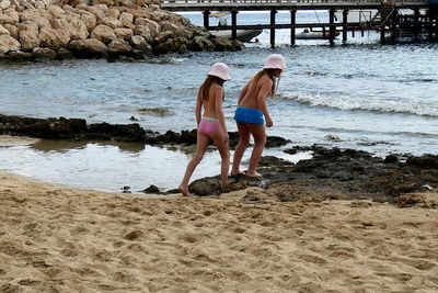 Rear view of mother and daughter on beach