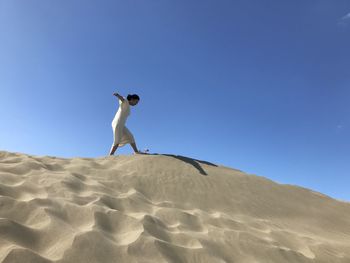 Low angle view of woman on sand against clear sky