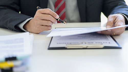 Midsection of man holding paper on table