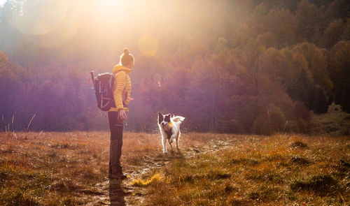 Full length of woman standing with dog on field