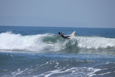 Man surfing in sea against sky