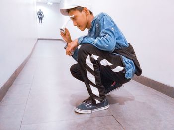 Side view of young man looking away while sitting on floor