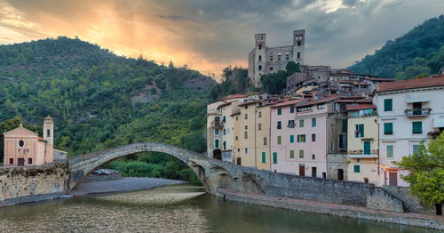 Bridge over river by buildings in city against sky