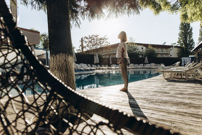 Woman standing by swimming pool on sunny day at resort