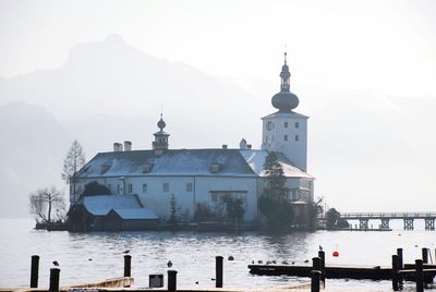 Church by lake against sky during winter