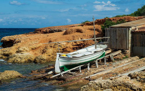 Boat moored on beach against sky