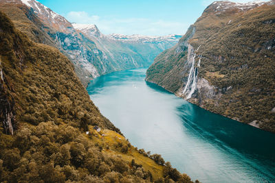 Scenic view of fjord, waterfall and mountains against sky