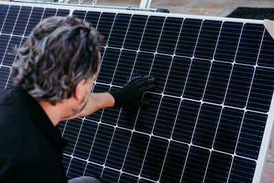 Back view of mature technician man checking solar panels for self consumption.renewable energy