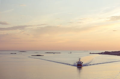 Boat sailing in sea against sky during sunset